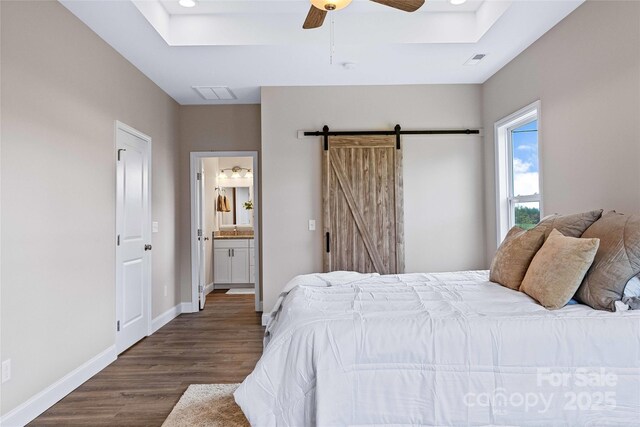 bedroom with visible vents, a tray ceiling, baseboards, and wood finished floors