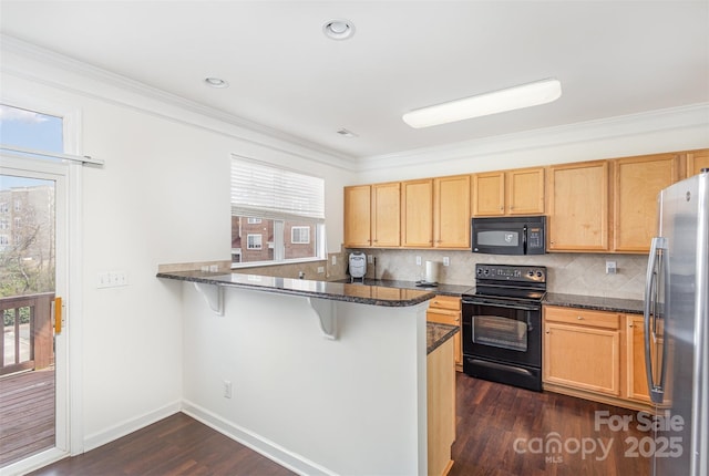 kitchen with a breakfast bar, a peninsula, black appliances, and tasteful backsplash