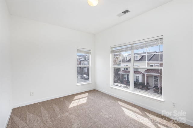 carpeted spare room with baseboards and visible vents