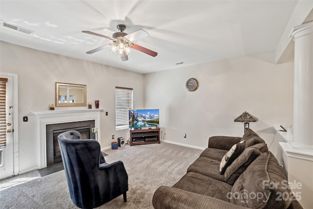 carpeted living area featuring a fireplace, decorative columns, visible vents, and a ceiling fan