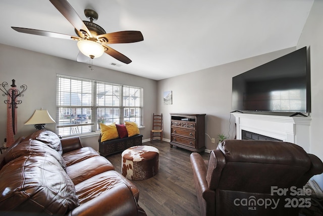 living room featuring visible vents, a ceiling fan, wood finished floors, a fireplace, and baseboards