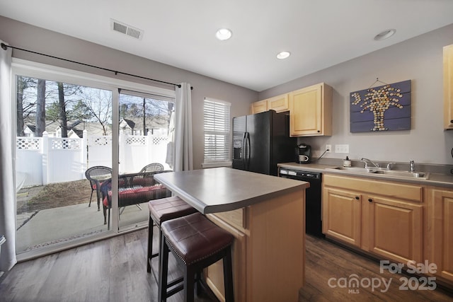 kitchen featuring light brown cabinets, visible vents, a kitchen island, a sink, and black appliances