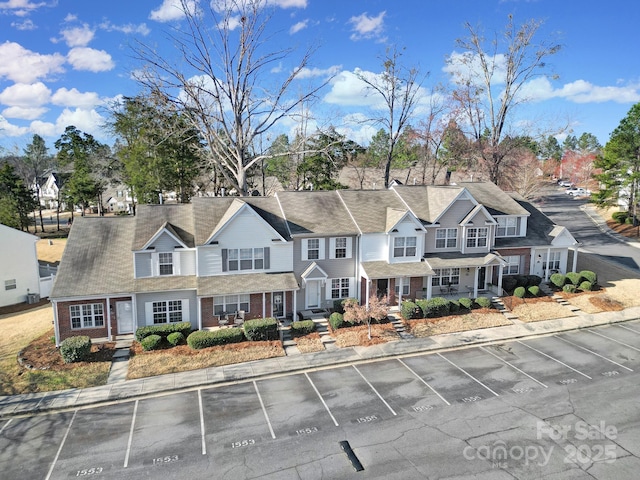 view of front facade featuring a residential view, brick siding, and uncovered parking