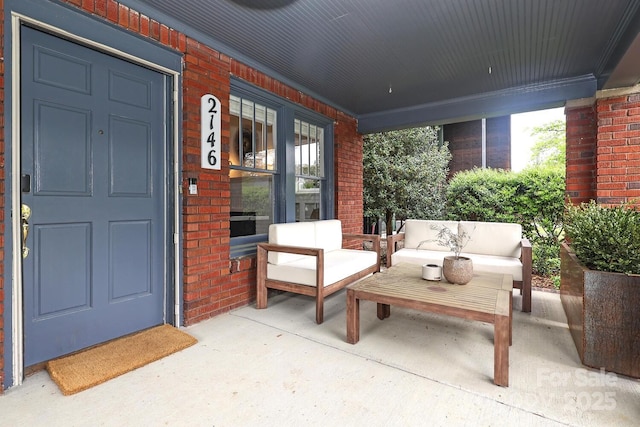 view of exterior entry featuring covered porch, an outdoor living space, and brick siding