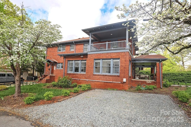 back of house featuring a balcony and brick siding