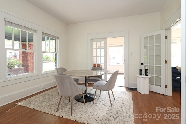 dining space with crown molding, baseboards, wood finished floors, and visible vents