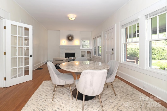 dining area with baseboards, ornamental molding, wood finished floors, and a fireplace