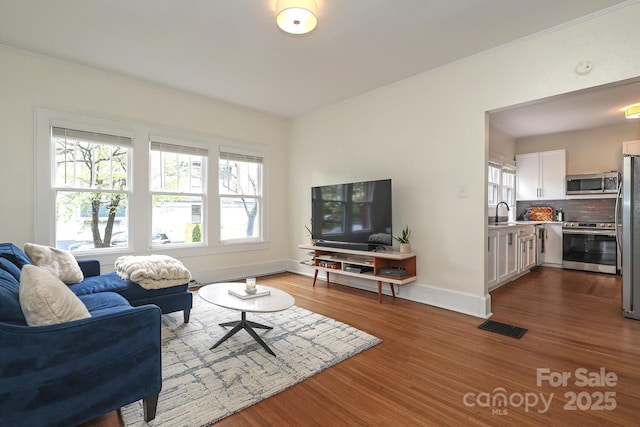 living room with visible vents, dark wood finished floors, crown molding, and baseboards