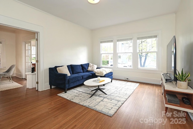 living room with crown molding, baseboards, and wood finished floors