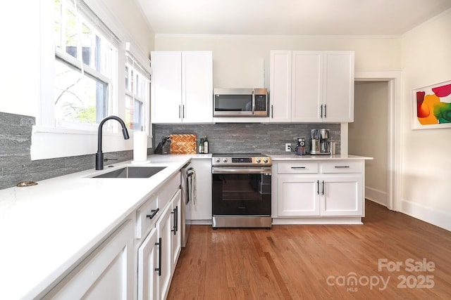 kitchen with a sink, backsplash, stainless steel appliances, and white cabinetry