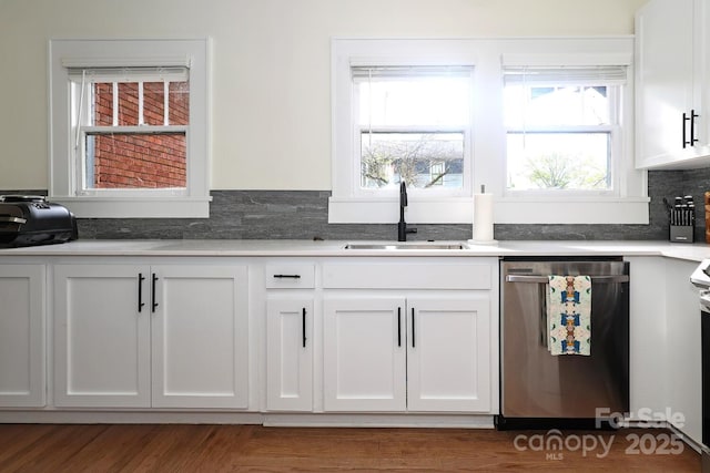 kitchen featuring light countertops, white cabinetry, a sink, and dishwasher