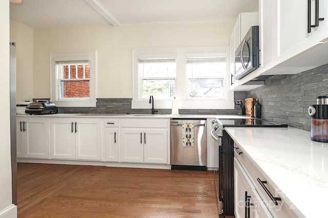 kitchen featuring a sink, appliances with stainless steel finishes, light wood-type flooring, and white cabinetry