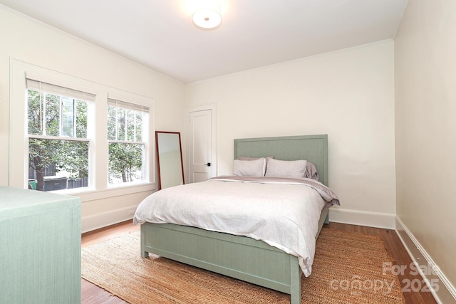 bedroom with crown molding, baseboards, and wood finished floors