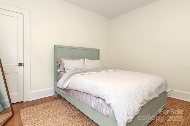 bedroom with crown molding, baseboards, and wood finished floors
