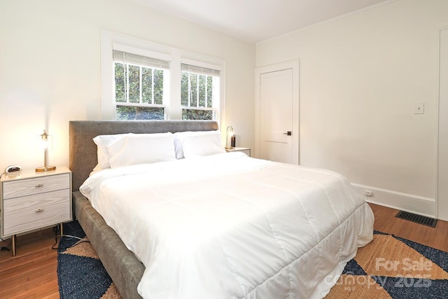 bedroom with visible vents, baseboards, and wood finished floors