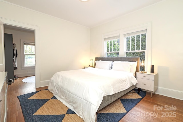 bedroom with crown molding, multiple windows, and wood finished floors