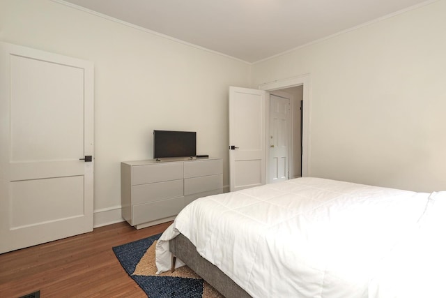 bedroom featuring baseboards, ornamental molding, and wood finished floors