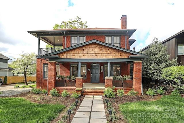 view of front of property with a balcony, a chimney, a porch, and brick siding