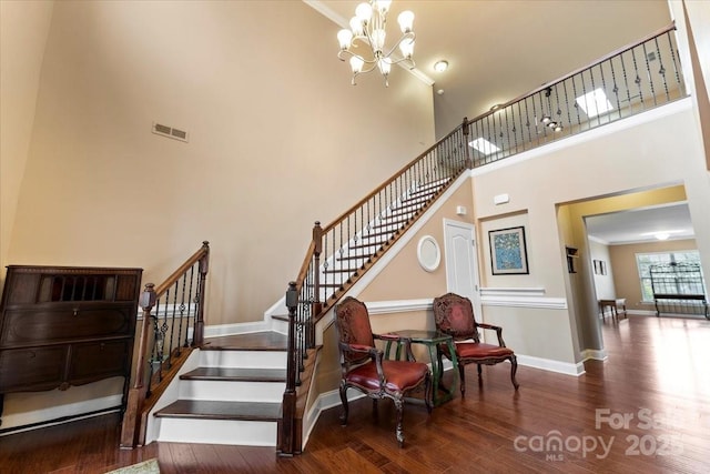 stairs featuring visible vents, a high ceiling, an inviting chandelier, wood finished floors, and baseboards