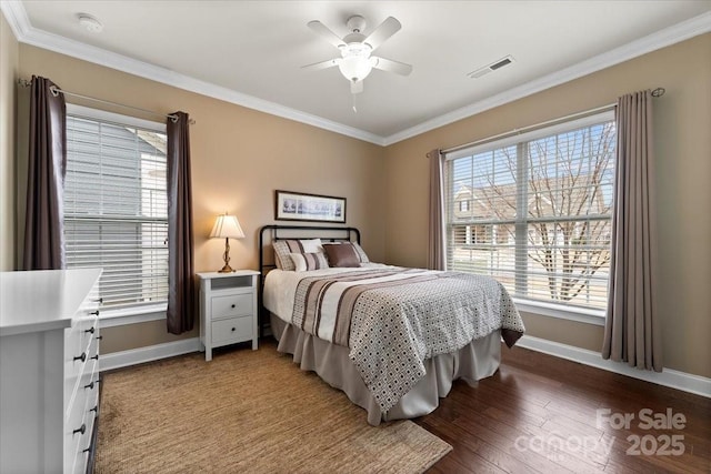 bedroom with baseboards, wood finished floors, visible vents, and crown molding