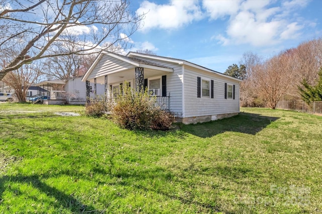 view of home's exterior featuring a porch, a lawn, and fence