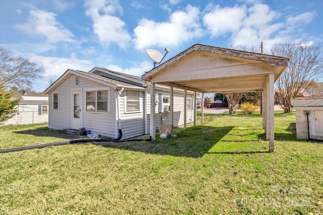 back of house featuring a carport, fence, and a lawn