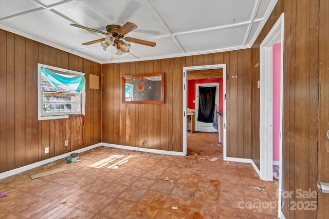 empty room with ceiling fan, wooden walls, baseboards, and tile patterned floors