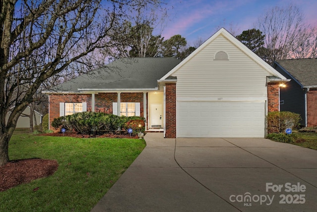 single story home with brick siding, an attached garage, concrete driveway, and a front yard