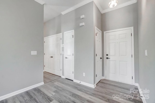 foyer entrance with baseboards, ornamental molding, and wood finished floors