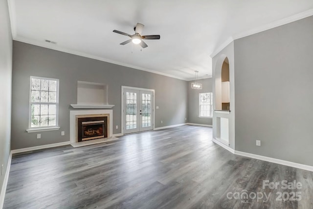 unfurnished living room with crown molding, visible vents, dark wood-type flooring, a fireplace with flush hearth, and baseboards