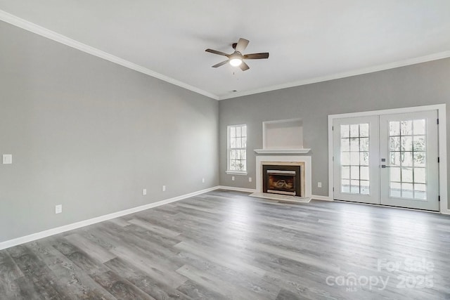 unfurnished living room featuring ornamental molding, french doors, baseboards, and wood finished floors