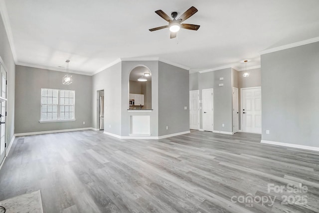 unfurnished living room featuring a ceiling fan, crown molding, baseboards, and wood finished floors