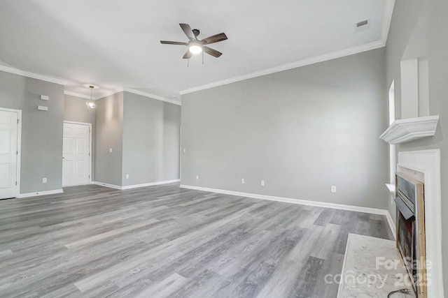 unfurnished living room with wood finished floors, a fireplace with flush hearth, a ceiling fan, baseboards, and crown molding