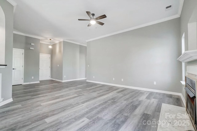 unfurnished living room with wood finished floors, a ceiling fan, a fireplace with flush hearth, visible vents, and baseboards