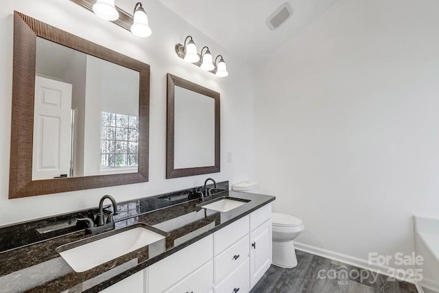 full bathroom featuring double vanity, a bathing tub, a sink, and toilet