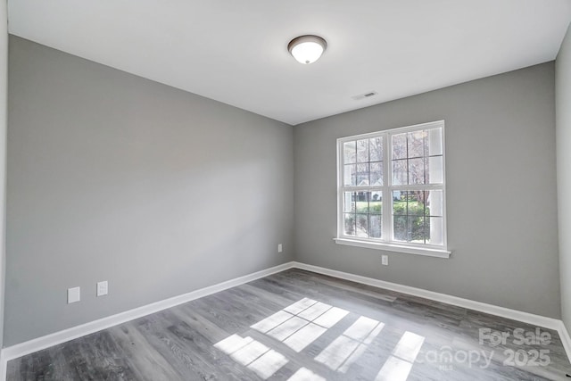 unfurnished room with visible vents, baseboards, and wood finished floors