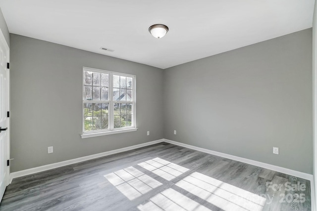 unfurnished room with visible vents, baseboards, and wood finished floors