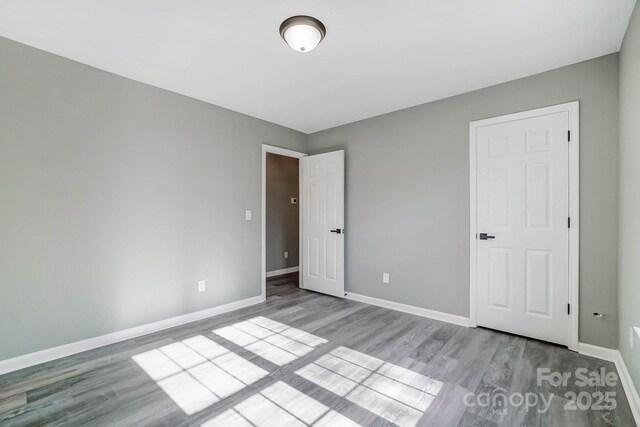 unfurnished bedroom featuring wood finished floors and baseboards