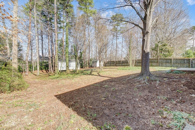 view of yard featuring a storage shed, fence, and an outdoor structure