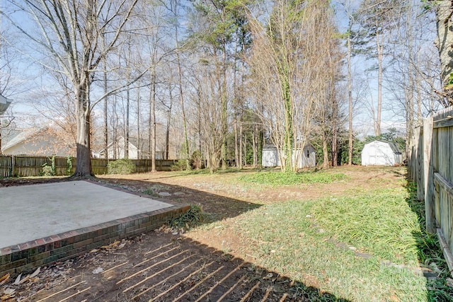 view of yard with a fenced backyard, an outdoor structure, a storage shed, and a patio