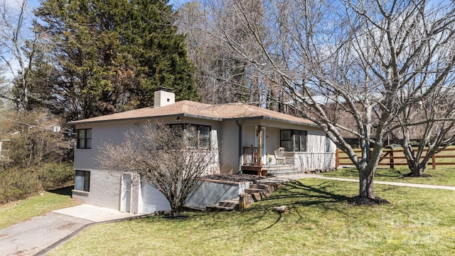 view of front of home featuring a chimney, stucco siding, a front yard, a garage, and driveway