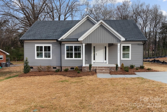 view of front facade featuring roof with shingles, covered porch, a front lawn, crawl space, and board and batten siding