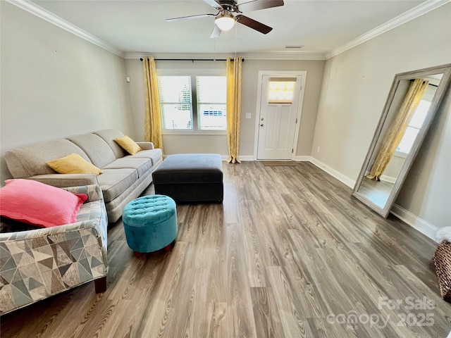 living room with wood finished floors, a ceiling fan, baseboards, visible vents, and crown molding