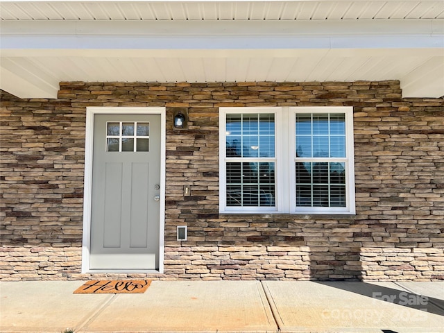 entrance to property with a porch and brick siding