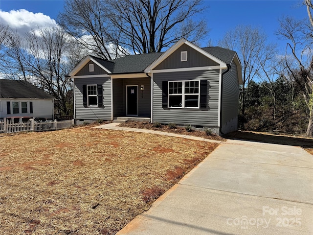 view of front of property with crawl space, fence, board and batten siding, and roof with shingles