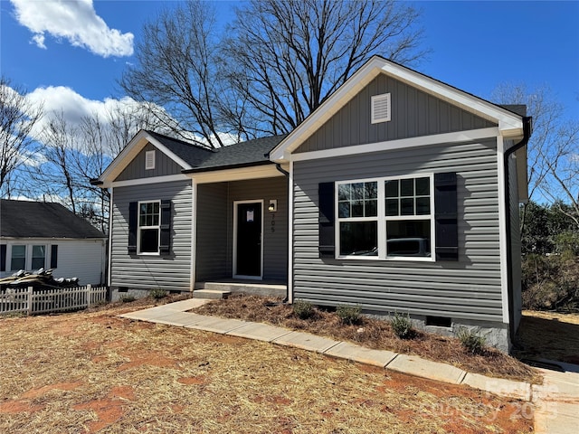 view of front of house featuring a shingled roof, crawl space, fence, and board and batten siding