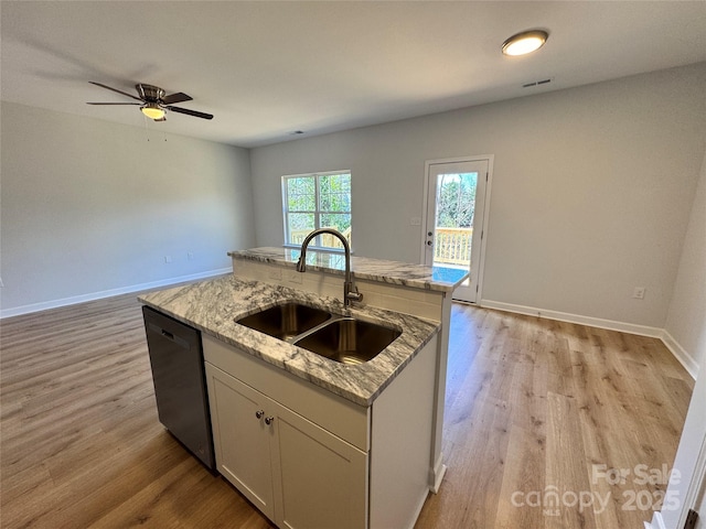 kitchen with an island with sink, light wood-style flooring, light stone counters, a sink, and stainless steel dishwasher