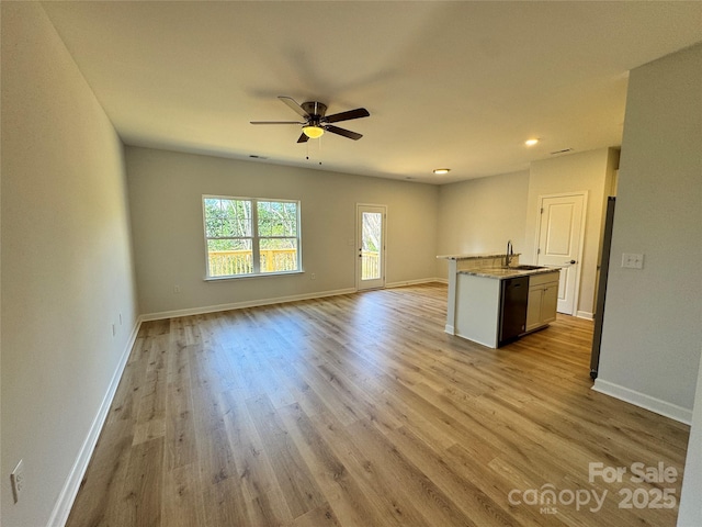 kitchen with wood finished floors, a sink, open floor plan, dishwasher, and an island with sink