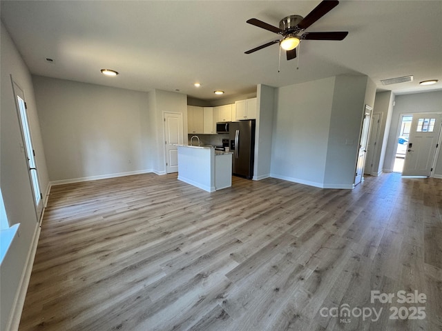 kitchen featuring stainless steel appliances, visible vents, white cabinetry, open floor plan, and light wood-type flooring