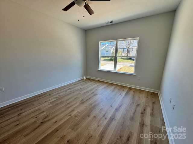 spare room featuring visible vents, ceiling fan, baseboards, and wood finished floors